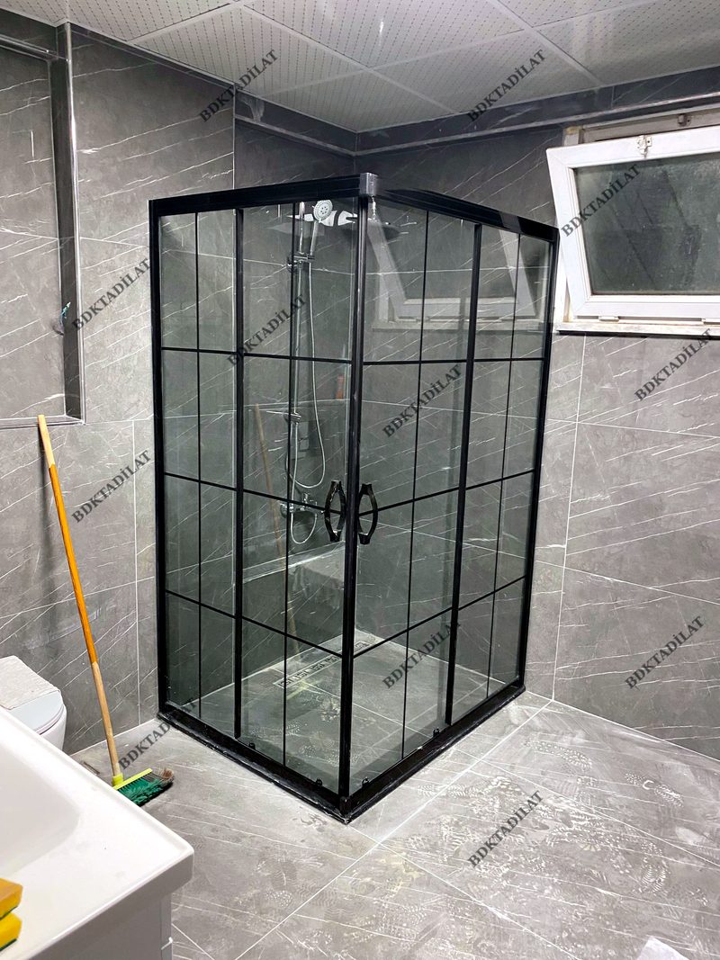 Tamamladığımız banyo — siyah çerçeveli kare desen duşakabin ve gri mermer görünümlü seramik